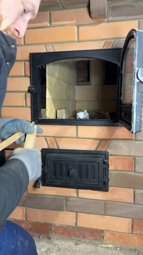A man loading firewood into a stove firebox. For lighting a test fire in a .. Stock Footage 327606175