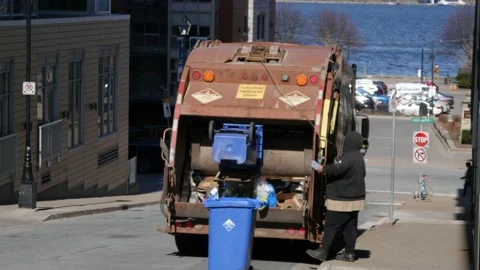 Man is loading a Garbage Track, and leans over a Plastic Bin full of Trash Stock Footage 240045731