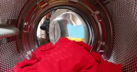 Man is loading laundry in washing machine. View from inside. The man goes to  Stock Footage 152856314