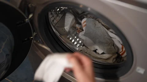 Man loading laundry into washing machine, preparing for household chores Stock Footage 293511615