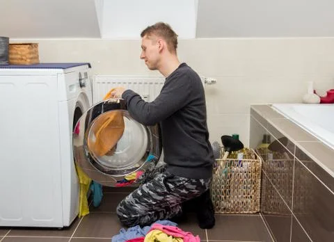 Man loading laundry into washing machine Stock Photos