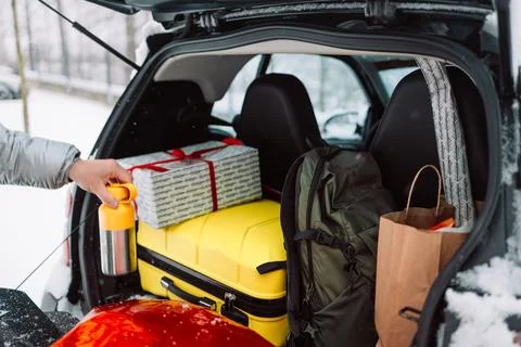 Man loading luggage and gift box into car trunk in winter Fotos de archivo