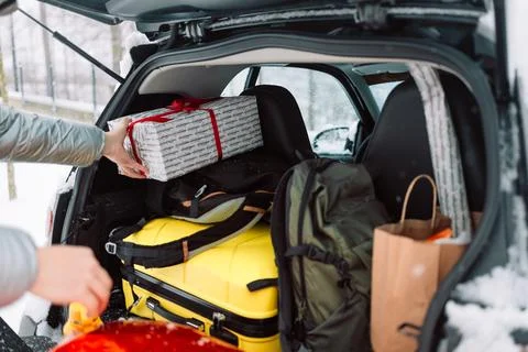 Man loading luggage and gift box into car trunk in winter Fotos de archivo