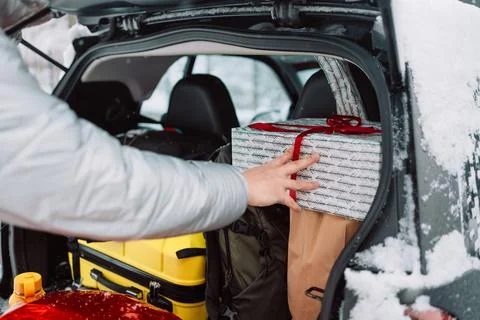 Man loading luggage and gift box into car trunk in winter Fotos de archivo