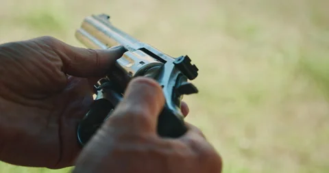 Man loading revolver cylinder with bullets outdoors during practice at shooting Stockbeeldmateriaal 311489143