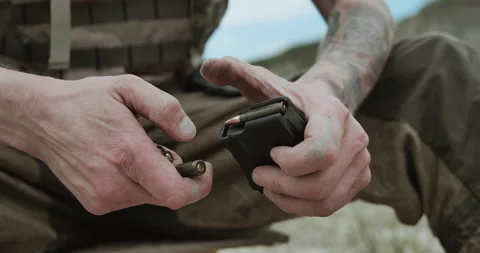 Man loading rifle cartridges into polymer magazine Stock Footage 134391515