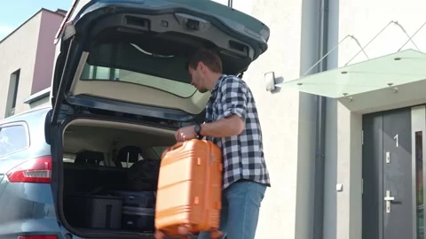 Man loading suitcase into car trunk, Packing luggage for travel Vídeo Stock 308326353