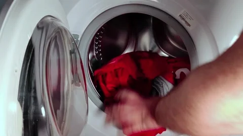 A man loading a washing machine with colored clothes Video stock 274198622