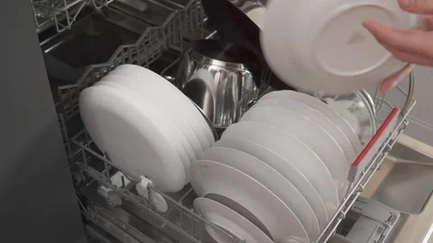 A man loads dirty dishes into the dishwasher. Stock Footage 252829370