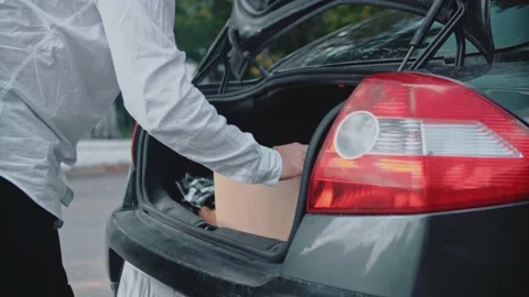 A man loads a parcel, puts a cardboard box in the trunk of a car. Stock Footage 150122207