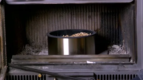 A man loads pellets into the fireplace with a white mug Stock Footage 225741730