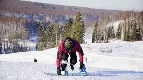 Man locking the mounts of snowboard standing on the snowy slope. Winter, sport Stock Footage 121239125