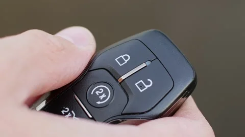 Man locks and unlocks car with key fob close-up on light gray background Video stock 166996391