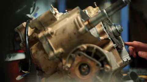 A man locksmith covers the joint between the engine and gearbox with sealant Vidéo 159984502