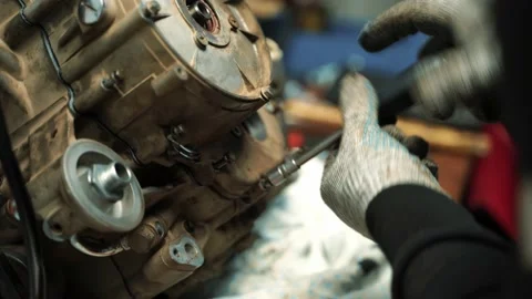 A man locksmith tightens the bolts on the engine cover, repairing an ATV motor Vidéo 159984384