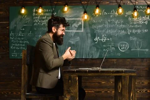 Man with long beard with computer on chalkboard. Bearded man work on laptop in Foto stock