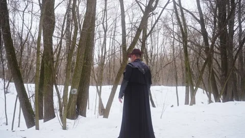 A man in a long black robe gesturing in the snowcovered forest Video stock 270484474
