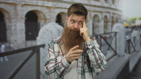 Man with long ginger beard points finger to temple while standing before su.. Stock Footage 315468589
