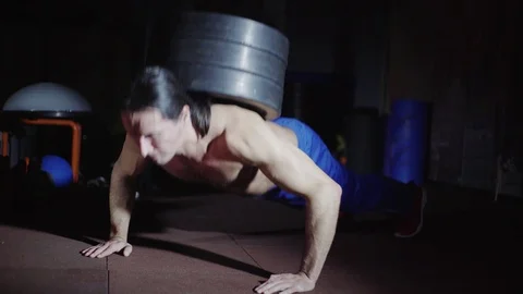 Man with long hair does push-ups with weight Stock Footage 123259127