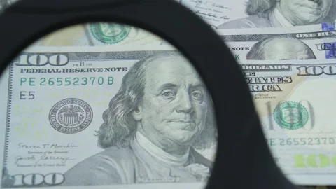 Man looking at 100 usd american dollar bills through a magnifying glass macro Stock Footage 204129030