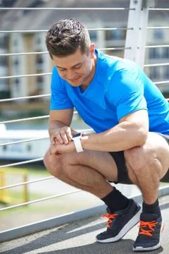 Man Looking At Activity Tracker Whilst Exercising In City Stock Photos