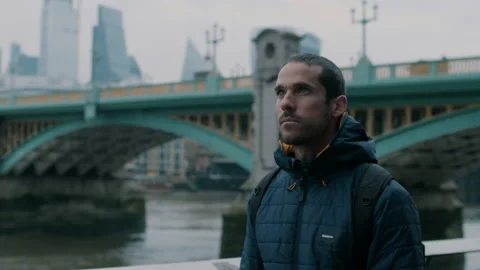Man looking up and thinking with bridge and river in background Stock Footage 130980518