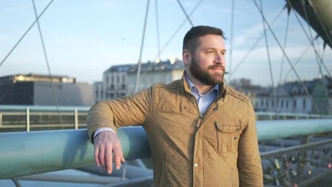Man looking around and at camera, standing on footbridge steadycam, pan shot 库存影片 72775664