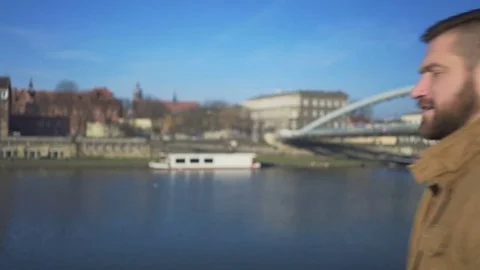 Man looking around on the background of the river and footbridge, behind shot Stock Footage 72709270
