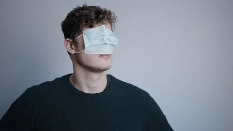 Man Looking Around Confused With Covid-19 Mask On His Eyes And Face. Video stock 162679761