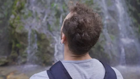 The man looking around in front of the waterfall. Stock Footage 212421382
