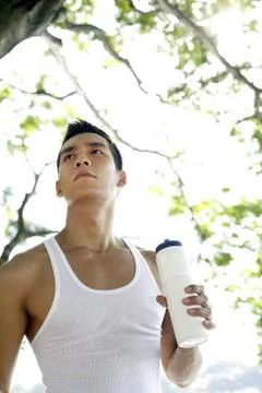 Man looking away while holding drinking bottle Stock Photos
