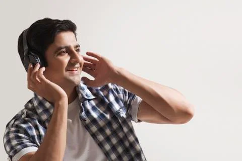 Man looking away while listening to music Stock Photos