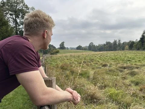 Man looking awayat fields under gloomy sky Stock Photos