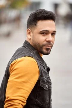 Man looking back while walking outdoors on the street. Fotos Stock