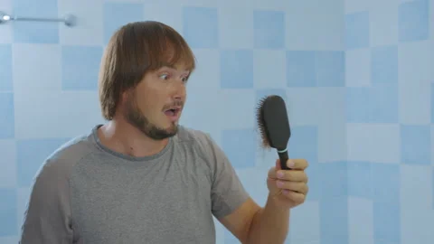 Man looking in bathroom mirror combing his hair styling or checking for hair Stock Footage 139111333