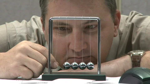 Man looking bored playing with kinetic balls Stock Footage