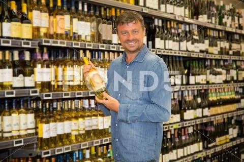 Man looking at bottle of wine in supermarket Stock Photos