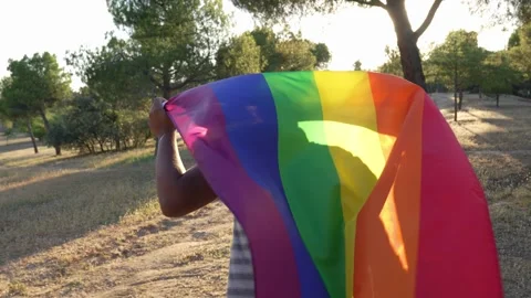 Man looking briefly at camera and start running with LGBTQ flag 動画素材 250467226