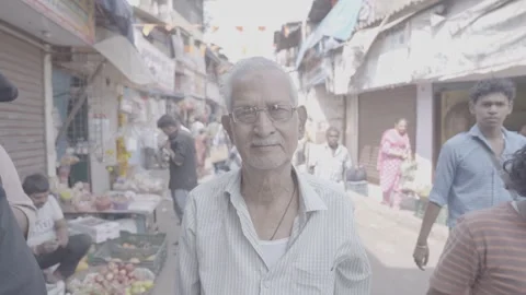 A man looking at the camera and people walking down the street in Mumbai, India Stock Footage 345390469