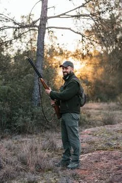 Man looking at camera and smiling while holding shotgun during hunting. Stock Photos