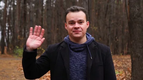 Man looking at camera and waving hand in autumn park Stock Footage 145813017