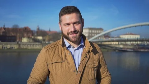 Man looking at camera on the background of the river and footbridge 動画素材 72709233