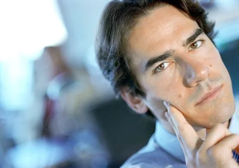 Man looking into camera, fingers on cheek, close-up. Stock Photos