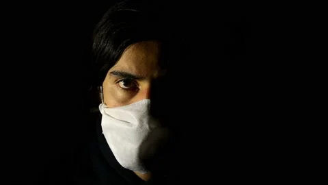 Man looking at camera putting and taking out his face mask. Black background. Stock Footage 134217583