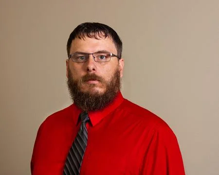 Man looking at the camera while wearing a red shirt and a tie Stock Photos