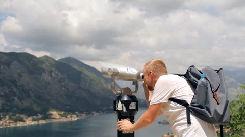Man is looking at the coin binoculars view of the mountain lake Video stock 92142394