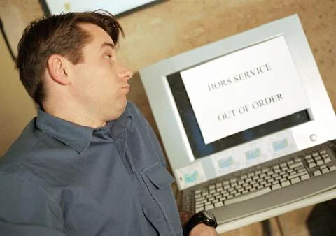 Man looking at computer screen with "out of order" sign on screen Stockfoto's