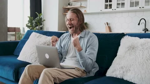 A man looking concerned looking at the screen and then exclaims yes, smiling. Stock Footage 239651900