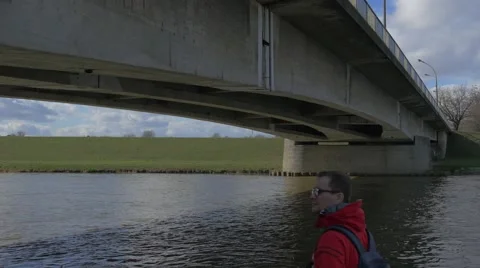 Man is Looking at Concrete Old Bridge Water Flows Under Bridge Green Bank Bare Stock Footage 60914795