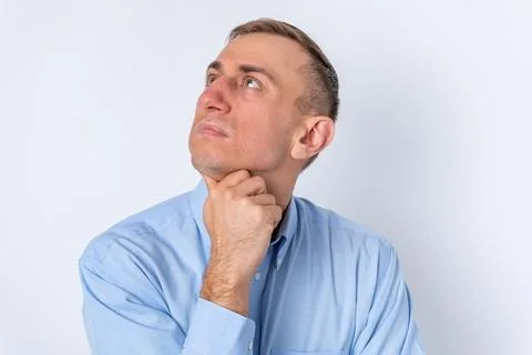 Man looking up contemplative with a thoughtful expression and hand on chin,.. Stock Photos